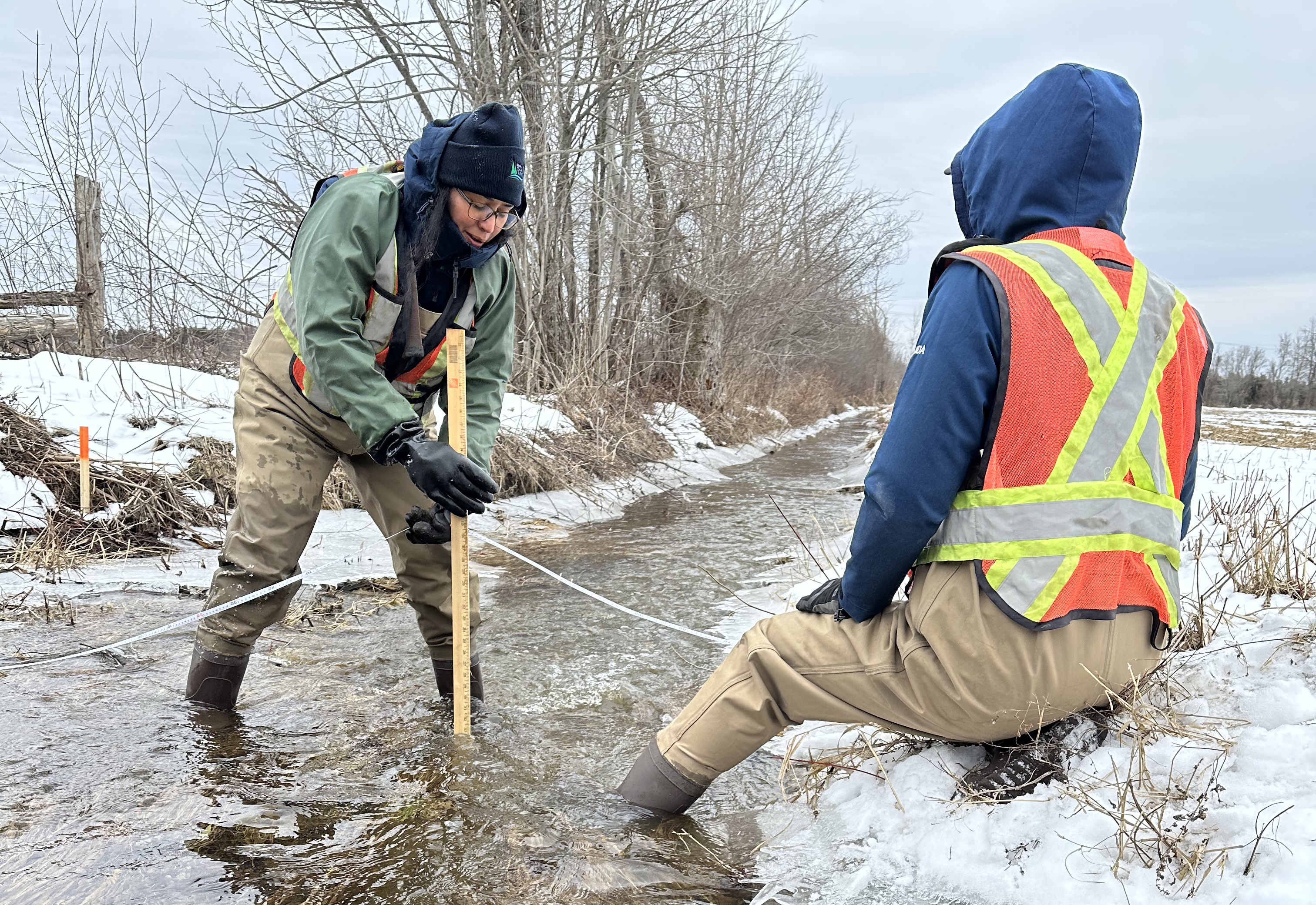 Two staff in a stream assess depth and width